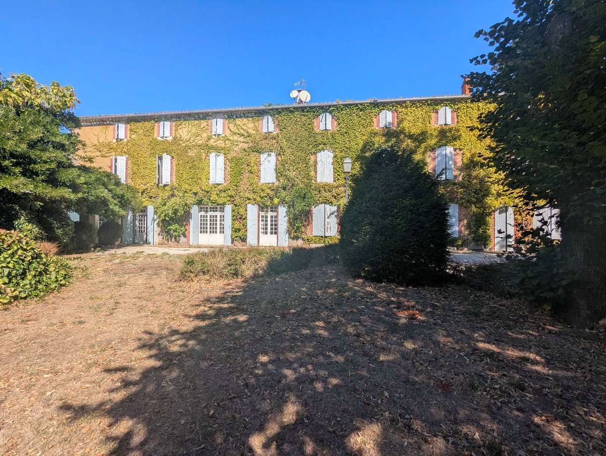 Le parc et la maison volets ouverts, vus depuis le fond de la propriété
